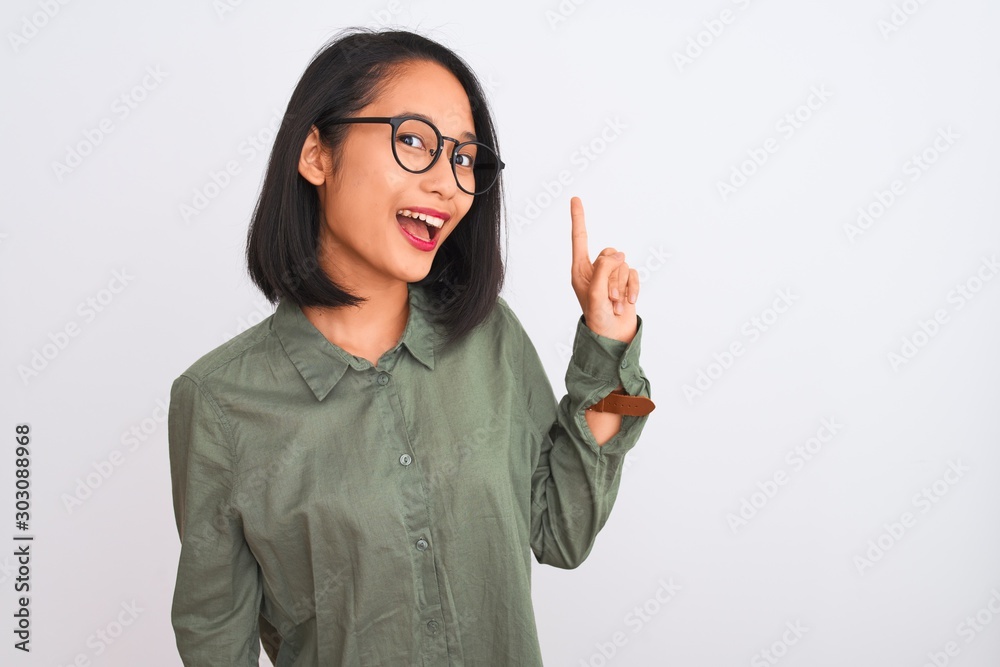 Young chinese woman wearing green shirt and glasses over isolated white background pointing finger up with successful idea. Exited and happy. Number one. Young chinese woman wearing green shirt and glasses over isolated white background pointing finger up with successful idea. Exited and happy. Number one.