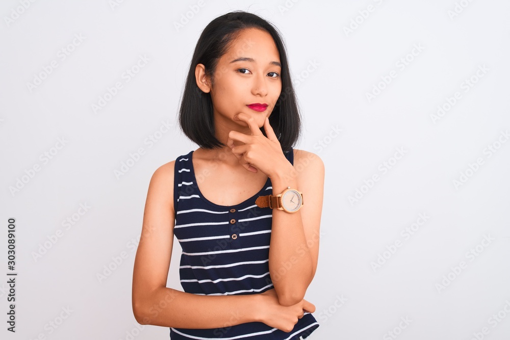 Young chinese woman wearing striped t-shirt standing over isolated white background looking confident at the camera with smile with crossed arms and hand raised on chin. Thinking positive. Young chinese woman wearing striped t-shirt standing over isolated white background looking confident at the camera with smile with crossed arms and hand raised on chin. Thinking positive.