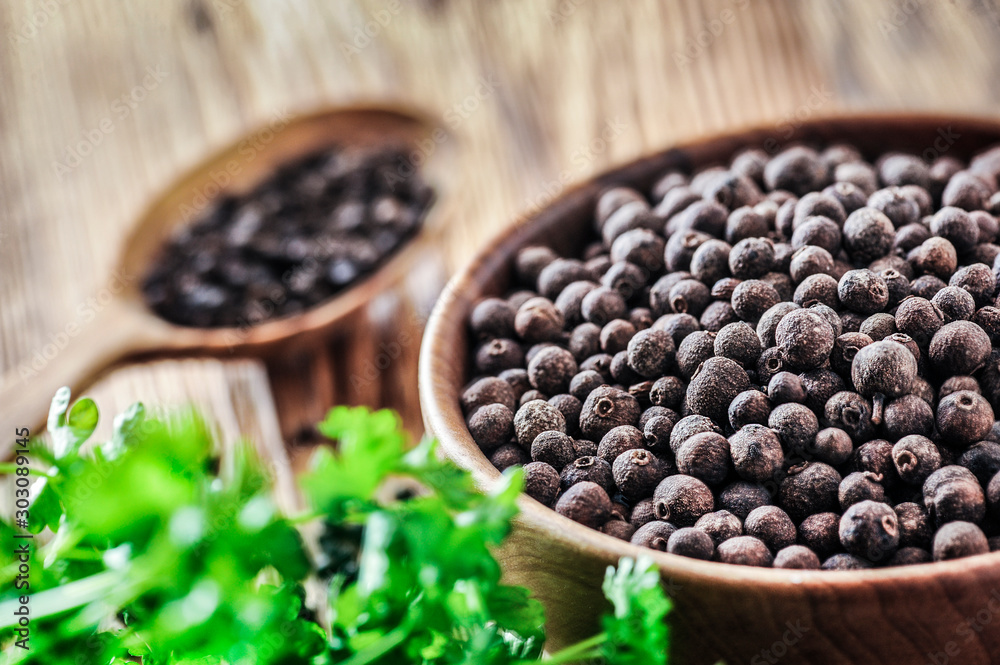 Black pepper. Pile of black pepper in wooden bowl. Wood spoon. full of pepper in background with green leaf. Black pepper. Pile of black pepper in wooden bowl. Wood spoon. full of pepper in background with green leaf.