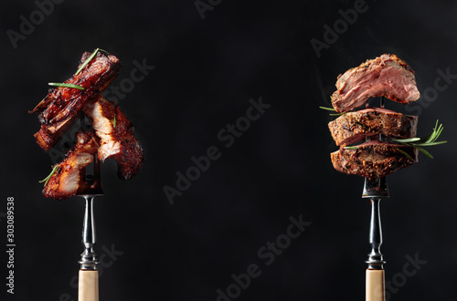Grilled pork belly and beef steak with rosemary on a black background.