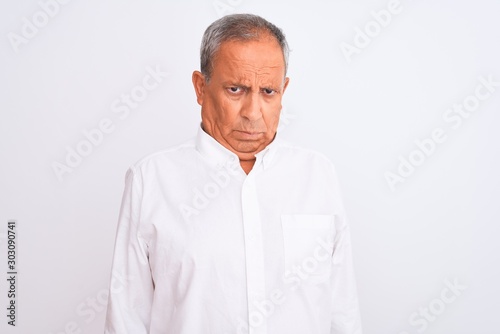Senior grey-haired man wearing elegant shirt standing over isolated white background skeptic and nervous, frowning upset because of problem. Negative person.