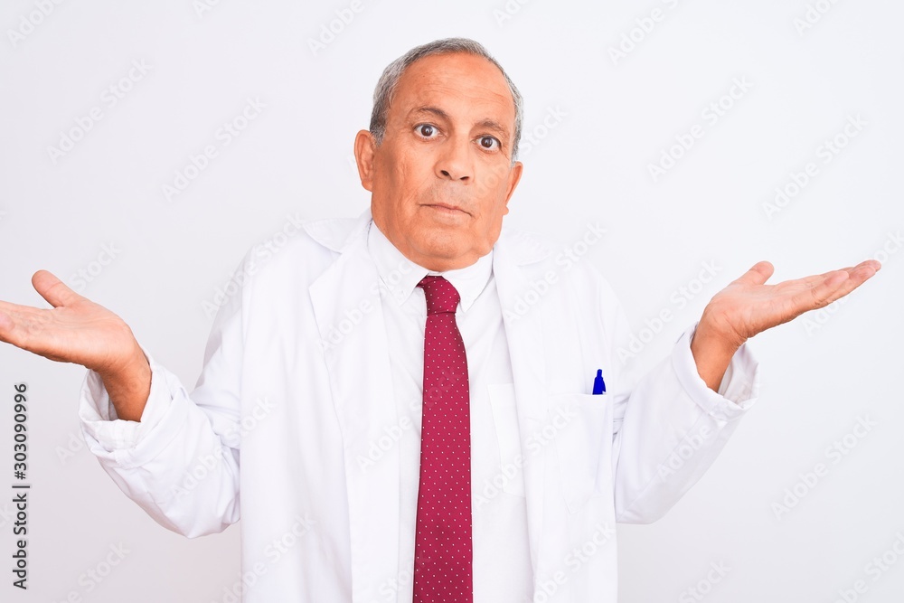 Senior grey-haired scientist man wearing coat standing over isolated white background clueless and confused expression with arms and hands raised. Doubt concept. Senior grey-haired scientist man wearing coat standing over isolated white background clueless and confused expression with arms and hands raised. Doubt concept.
