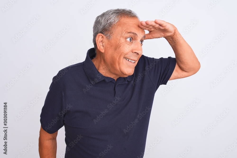 Senior grey-haired man wearing black casual polo standing over isolated white background very happy and smiling looking far away with hand over head. Searching concept. Senior grey-haired man wearing black casual polo standing over isolated white background very happy and smiling looking far away with hand over head. Searching concept.