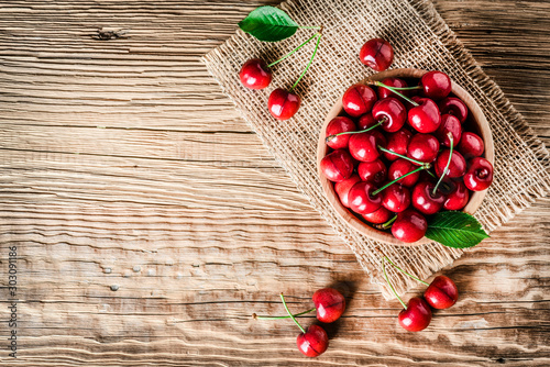 Fresh ripe cherry on wooden background. Top view of cherries in bowl .