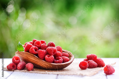 Ripe fresh raspberry in wooden rustic bowl on table.