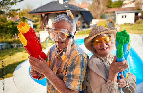 crazy senior people have fun on vacation playing with water gun