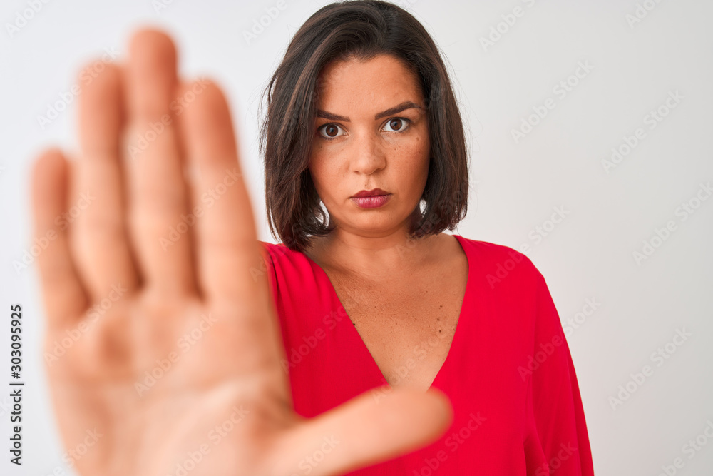 Young beautiful woman wearing red t-shirt standing over isolated white background with open hand doing stop sign with serious and confident expression, defense gesture Young beautiful woman wearing red t-shirt standing over isolated white background with open hand doing stop sign with serious and confident expression, defense gesture