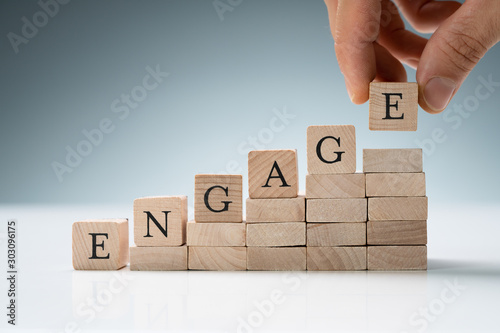 Person Arranging Wooden Blocks Showing Engage Text