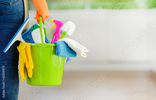Woman holding cleaning items in plastic bucket. Kitchen service washing concept with copy space.