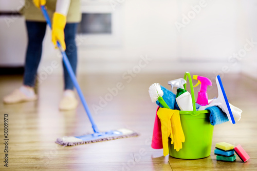 Bucket with cleaning items with modern kitchen and  background. Washing brush and spray set with copy space.