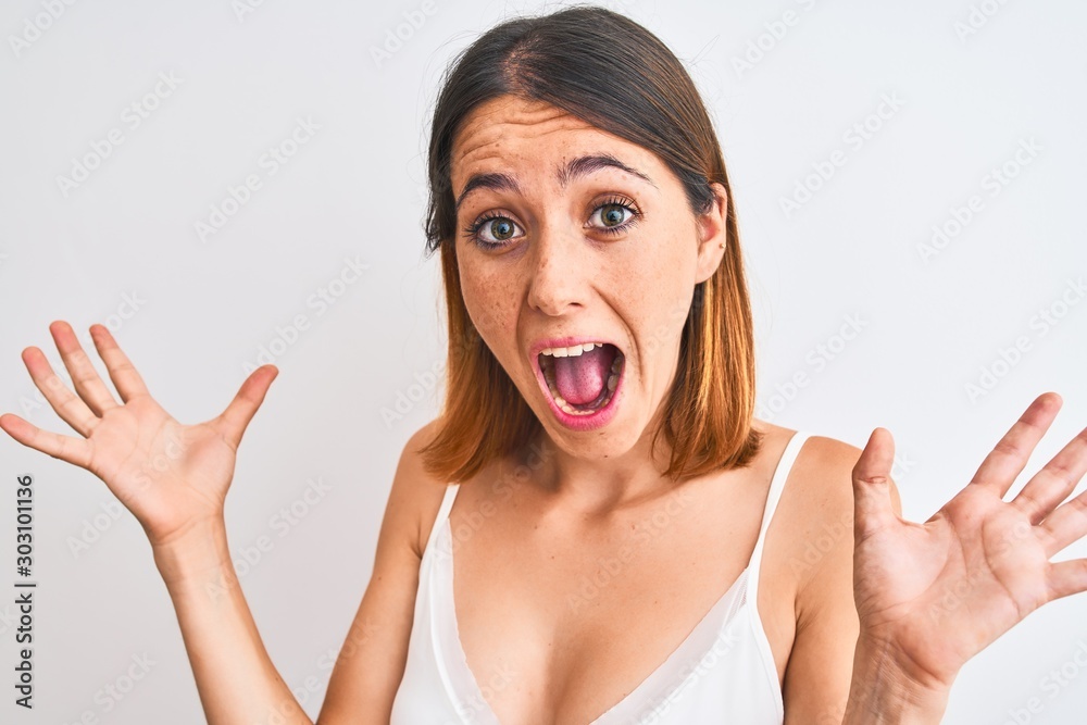 Beautiful redhead woman wearing casual white t-shirt over isolated background very happy and excited, winner expression celebrating victory screaming with big smile and raised hands Beautiful redhead woman wearing casual white t-shirt over isolated background very happy and excited, winner expression celebrating victory screaming with big smile and raised hands