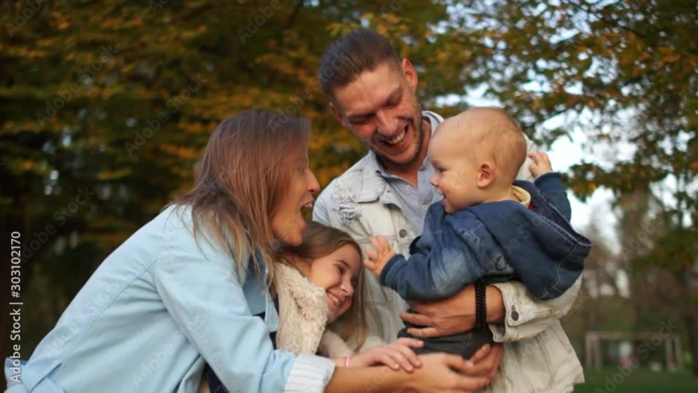 Young couple, toddler and teen girl cuddling in autumn park, happy family vacation. Family with two children in autumn park Young couple, toddler and teen girl cuddling in autumn park, happy family vacation. Family with two children in autumn park