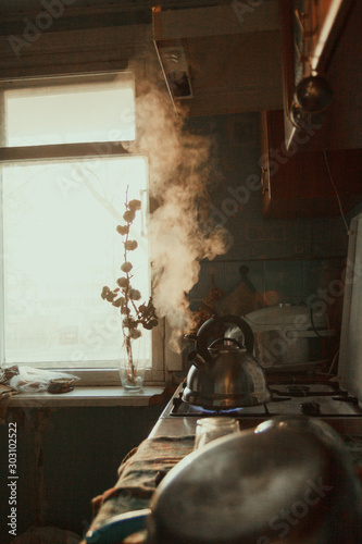  Russian cuisine. A metal kettle boils on the stove. Brown table with dishes that dry, blue tiles, sink