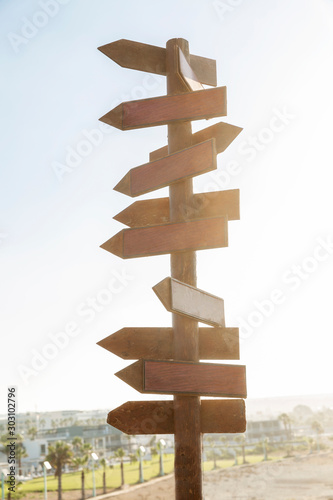 Empty wooden sign with direction signs on a blue sky background. Solar flare. Vertical.