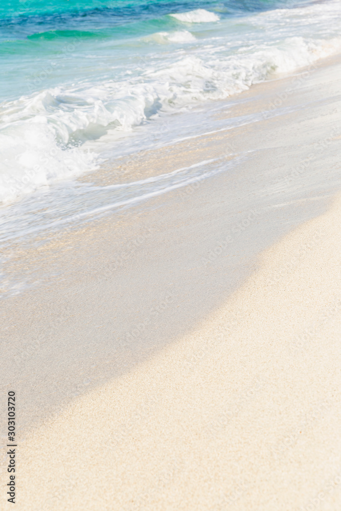 Turquoise sea wave surface on a sandy beach. Background. Space for text. Vertical.