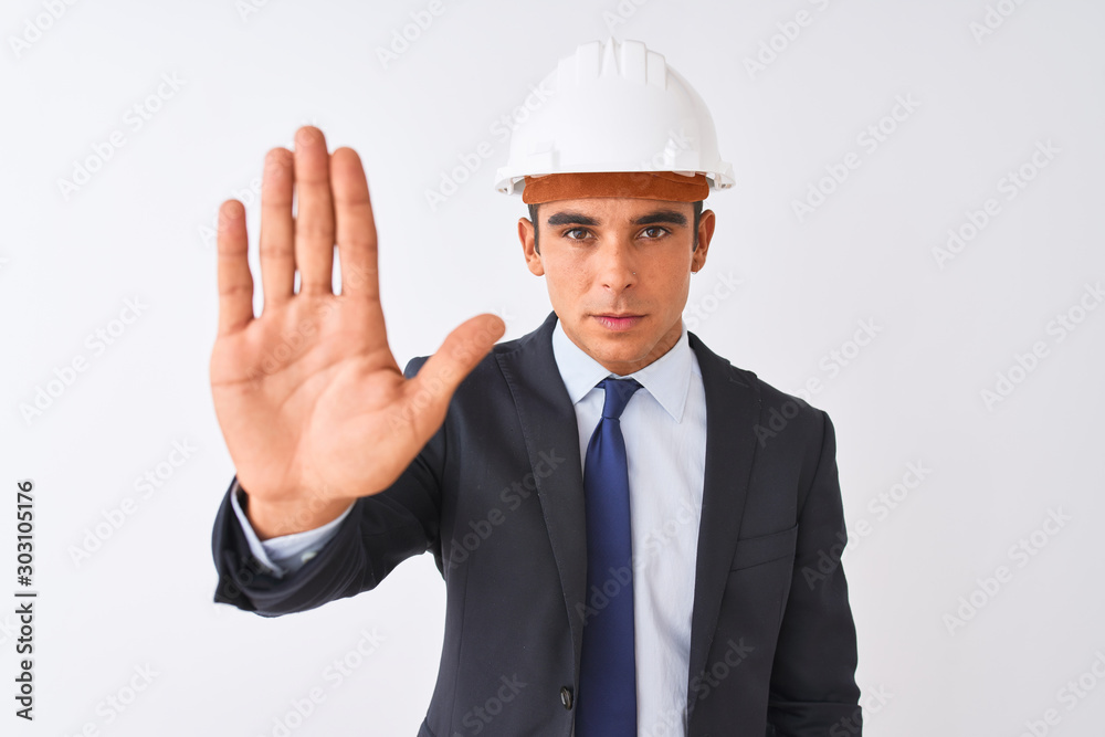 Young handsome architect man wearing suit and helmet over isolated white background doing stop sing with palm of the hand. Warning expression with negative and serious gesture on the face.