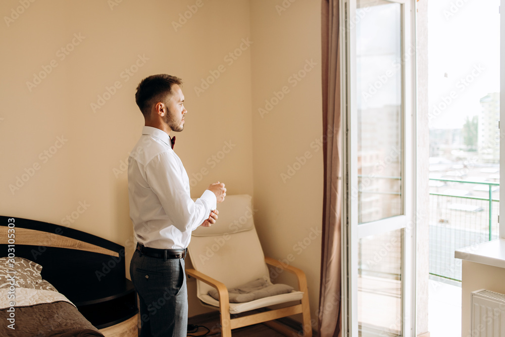 Handsome groom standing in the room in front of the window Handsome groom standing in the room in front of the window