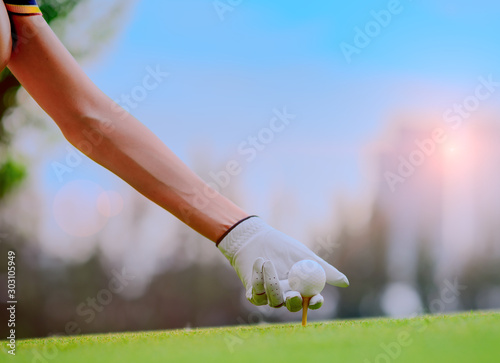 hand of young woman golf player holding golf ball laying on wooden tee pin on T-OFF, prepare and ready to hit the ball to the destination target