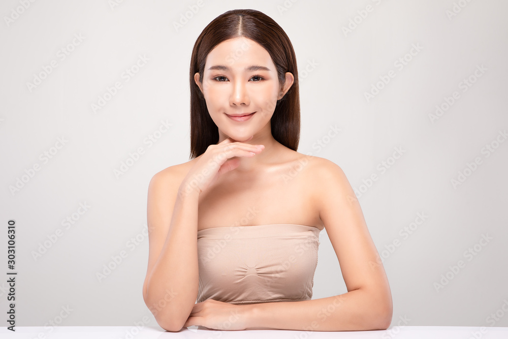 Obraz premium Beautiful Young Asian Woman Looking While Touching Chin feeling so happy and cheerful with healthy Clean and Fresh skin,isolated on gray background,Beauty Cosmetics Concept