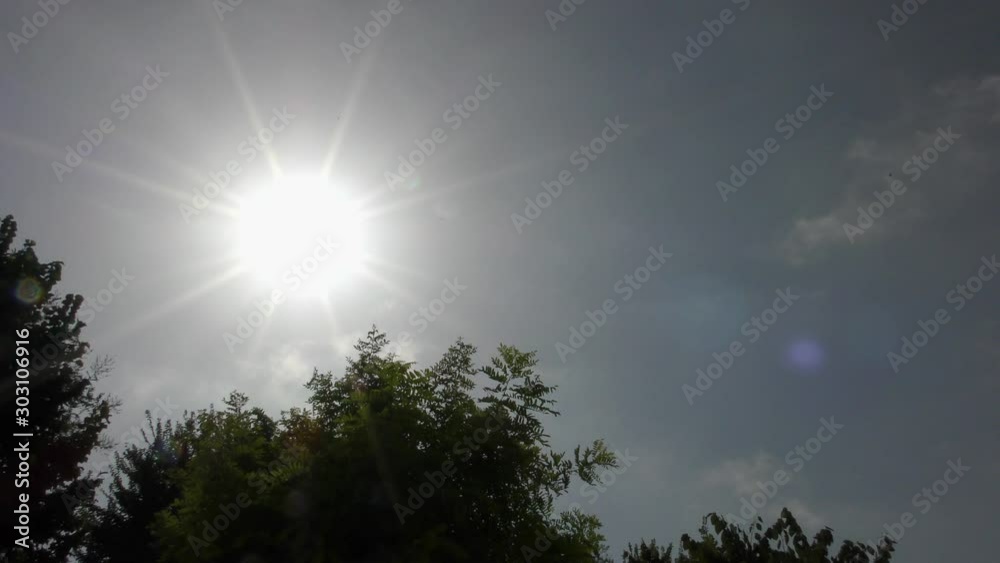 Crowns of trees against the background of the rays of the sun and summer sky with small clouds. Crowns of trees against the background of the rays of the sun and summer sky with small clouds.
