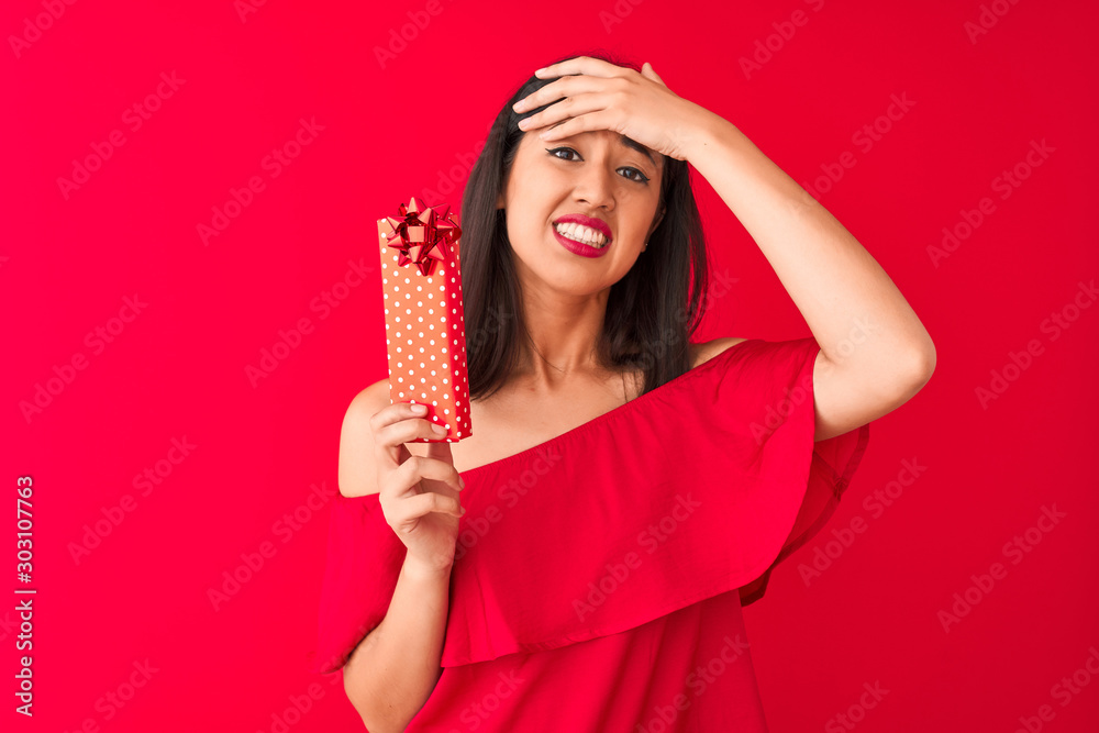 Young beautiful chinese woman holding valentine gift standing over isolated red background stressed with hand on head, shocked with shame and surprise face, angry and frustrated. Fear and upset Young beautiful chinese woman holding valentine gift standing over isolated red background stressed with hand on head, shocked with shame and surprise face, angry and frustrated. Fear and upset