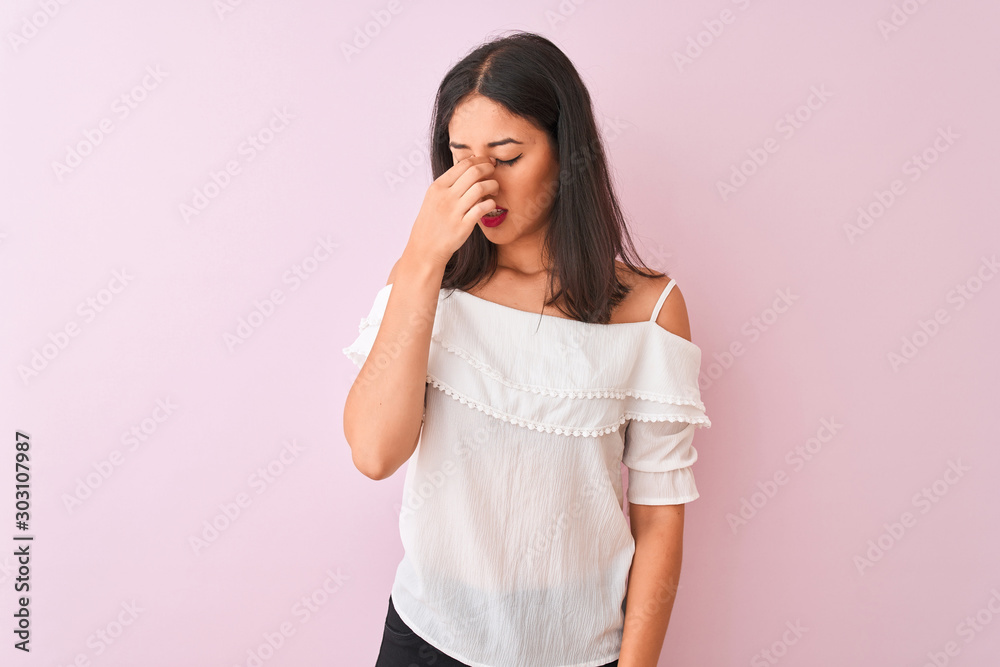 Beautiful chinese woman wearing white t-shirt standing over isolated pink background tired rubbing nose and eyes feeling fatigue and headache. Stress and frustration concept. Beautiful chinese woman wearing white t-shirt standing over isolated pink background tired rubbing nose and eyes feeling fatigue and headache. Stress and frustration concept.