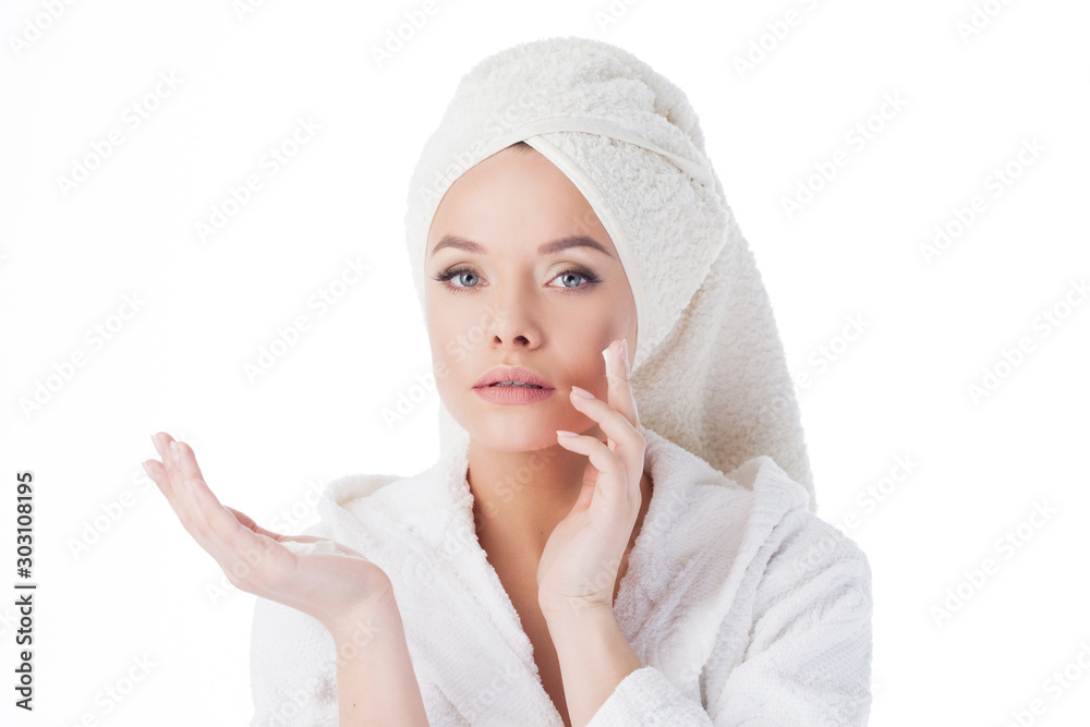 To use the cream after a shower. Portrait of a young attractive woman in a Bathrobe and a towel on her head. To use the cream after a shower. Portrait of a young attractive woman in a Bathrobe and a towel on her head.