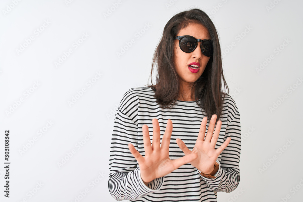 Fototapeta premium Chinese woman wearing striped t-shirt and sunglasses standing over isolated white background afraid and terrified with fear expression stop gesture with hands, shouting in shock. Panic concept.