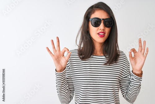 Chinese woman wearing striped t-shirt and sunglasses standing over isolated white background relax and smiling with eyes closed doing meditation gesture with fingers. Yoga concept.