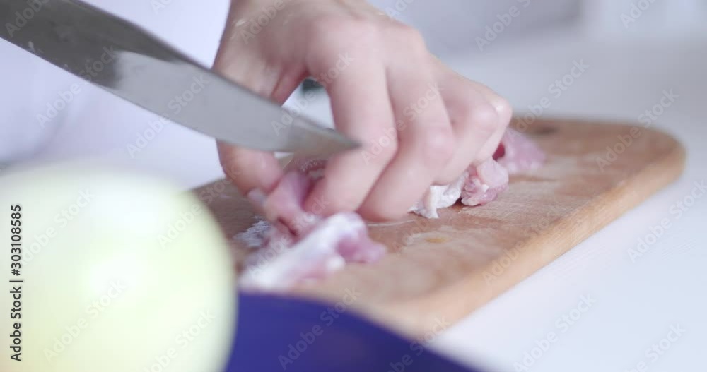 Beef fillet on the cut board. Woman`s hands with a knife slices a delicate beef fillet on the cut board. Beef meat on the table. Beef fillet on the cut board. Woman`s hands with a knife slices a delicate beef fillet on the cut board. Beef meat on the table.