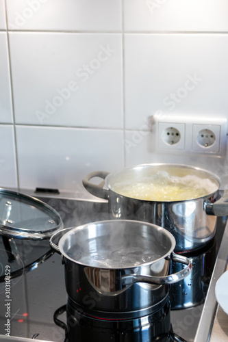 Mittagessen im dampfenden Kochtopf wird auf heißer Herdplatte in der Küche von einer Hausfrau für die Familie gekocht und zubereitet mit Verletzungsgefahr und Verbrennungsgefahr