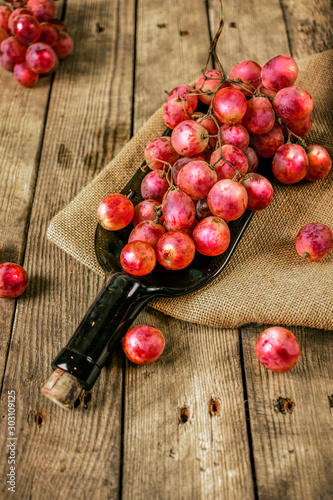 Red grapes on a tray in the form of a bottle on a wooden table