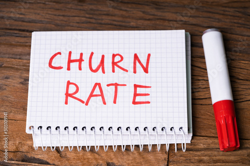 Εκτύπωση καμβά Churn Rate Text On Checkered Notepad With Marker Over Table