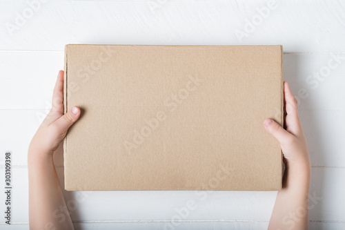 Rectangular cardboard box in children's hands. Top view, white background © somemeans