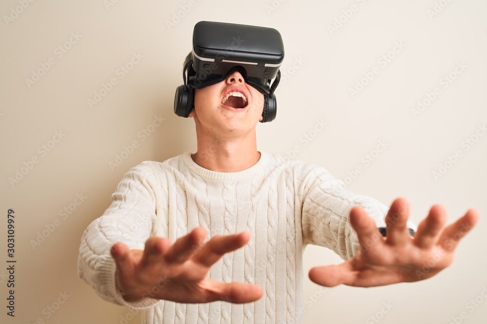 Young handsome teenager boy playing virtual reality game using goggles Young handsome teenager boy playing virtual reality game using goggles