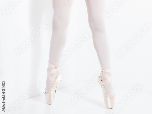 legs and feet with pink satin pointe shoes by a classic ballerina on tiptoe