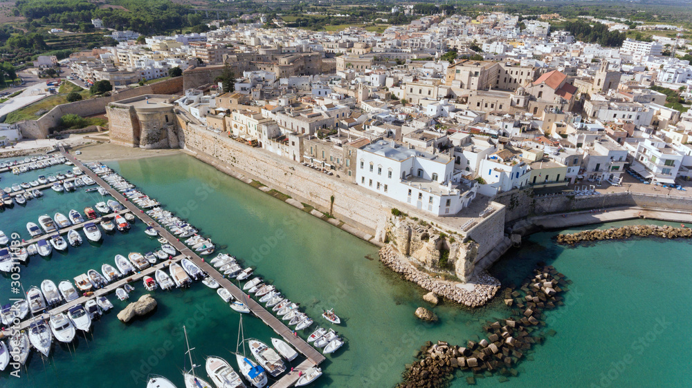 Aerial view of coastal historic town Otranto with castle, boats and yachts in marina, seafront promenade by Adriatic turquoise waters.