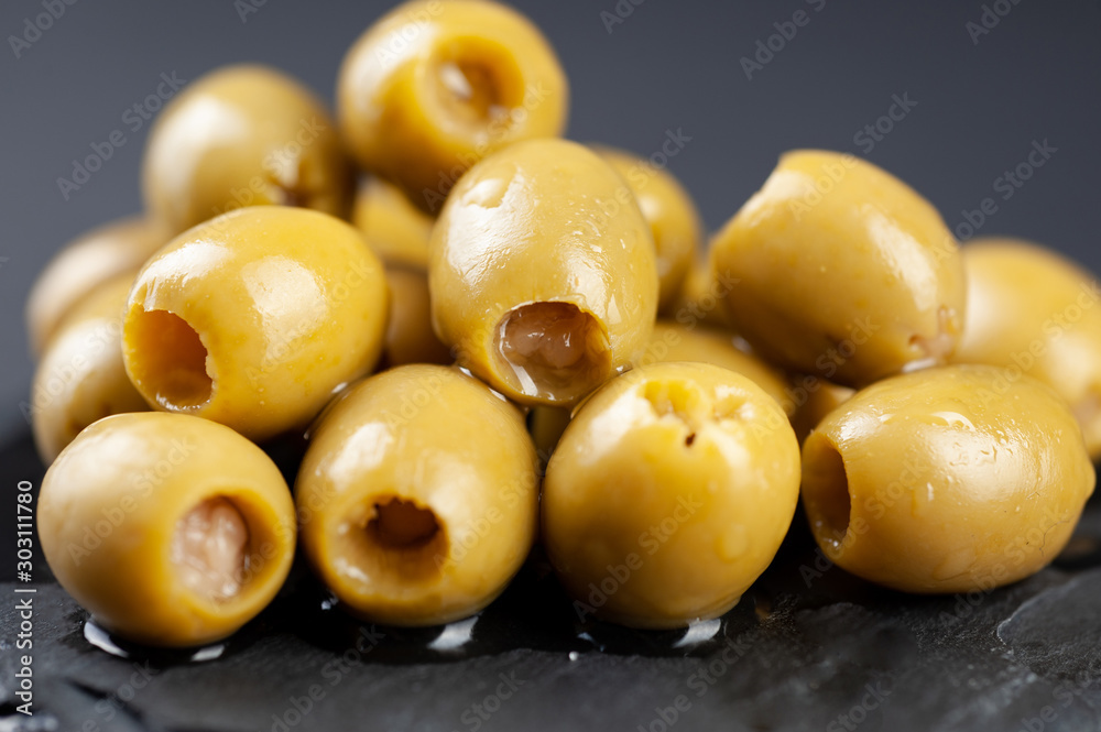several olives lie on a black board on a black background macro super macro