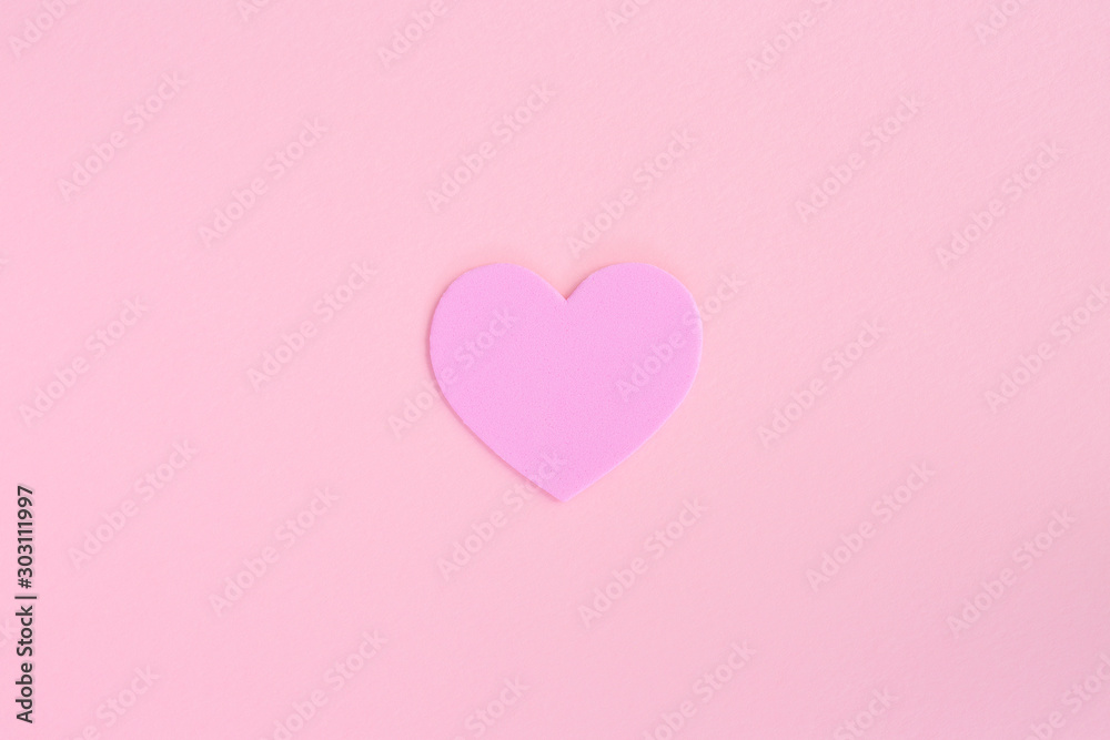 A single love heart in the centre of a pink background with copy space representing Valentines Day and romance