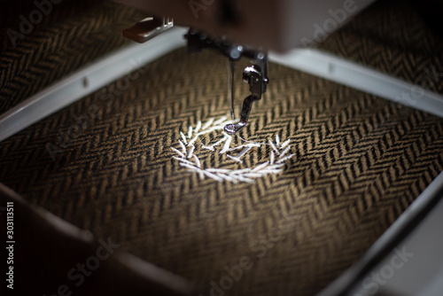 Embroidery design alphabet monogram M on brown fabrics embroider by machine. Close up