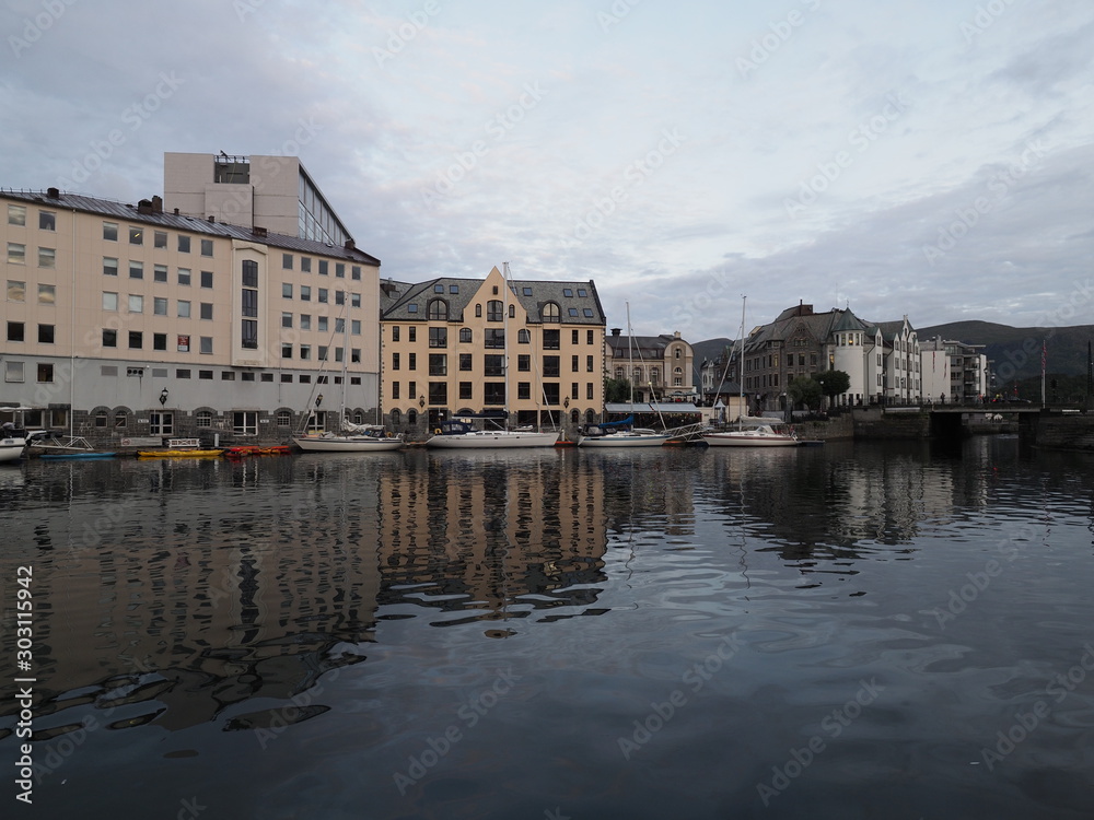 Yachts and secessionist center of european Alesund town reflected in water at Romsdal region in Norway