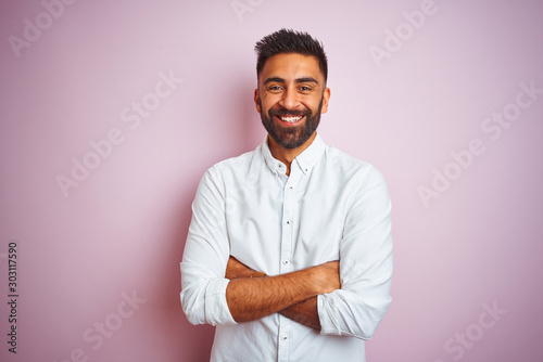 Young indian businessman wearing elegant shirt standing over isolated pink background happy face smiling with crossed arms looking at the camera. Positive person. photo