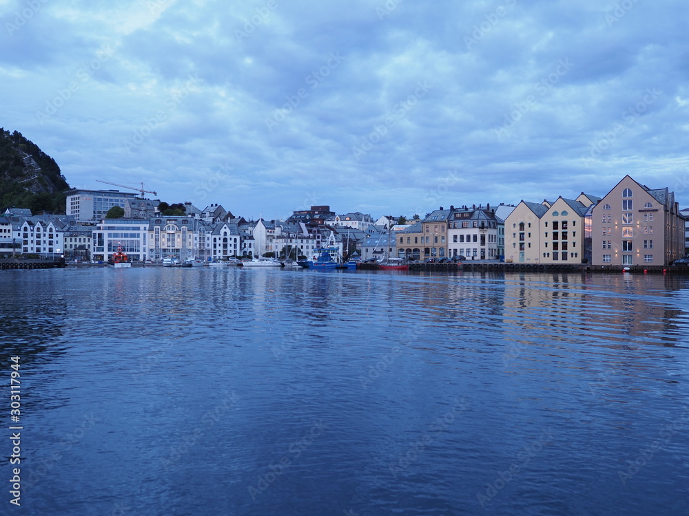 Scenic secessionist houses of european Alesund town reflected in water in Norway at blue hour