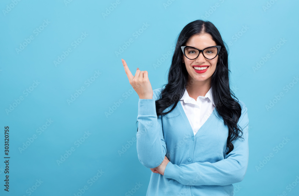 Young woman pointing at something on a blue background Young woman pointing at something on a blue background