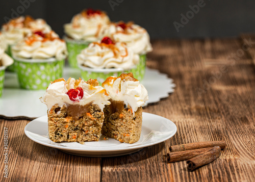 Carrot cupcakes with dried cherries and caramel on a wooden background