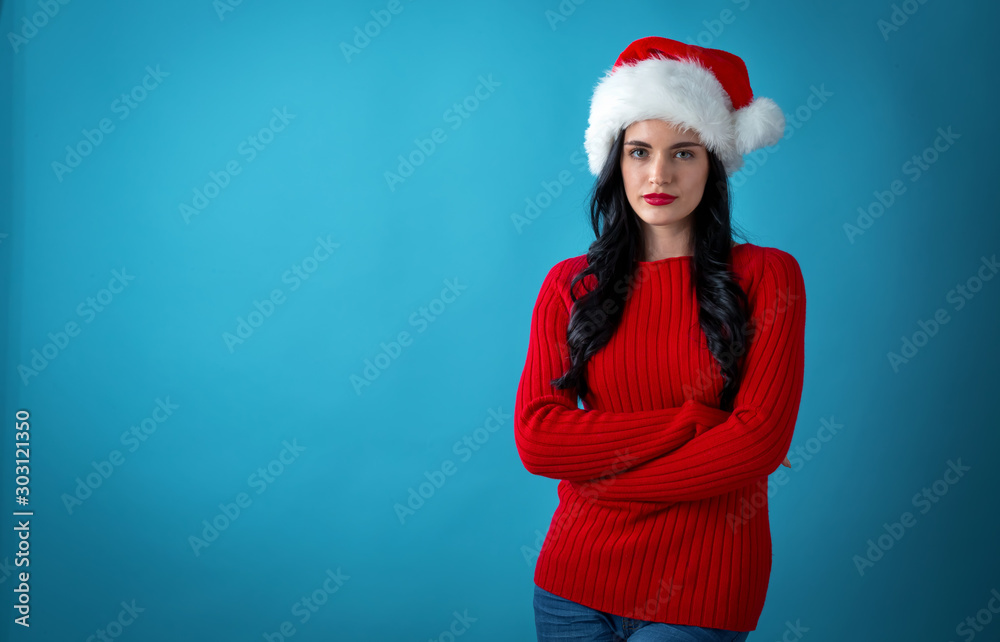 Young woman with a Santa hat on a dark blue background Young woman with a Santa hat on a dark blue background