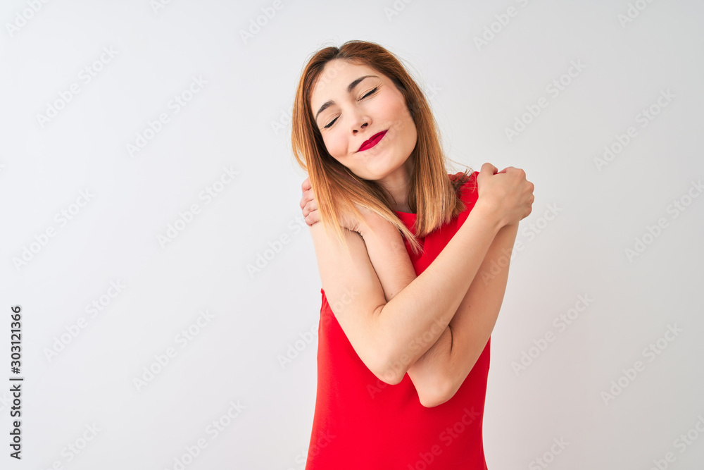 Redhead businesswoman wearing elegant red dress standing over isolated white background Hugging oneself happy and positive, smiling confident. Self love and self care Redhead businesswoman wearing elegant red dress standing over isolated white background Hugging oneself happy and positive, smiling confident. Self love and self care
