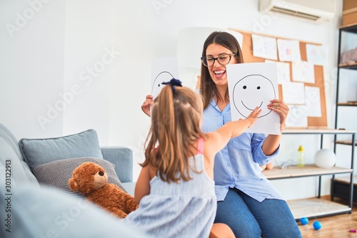 Young therapist woman speaking and treating child, counselor and behaviour correction at pedagogue payroom showing happy and sad faces photo