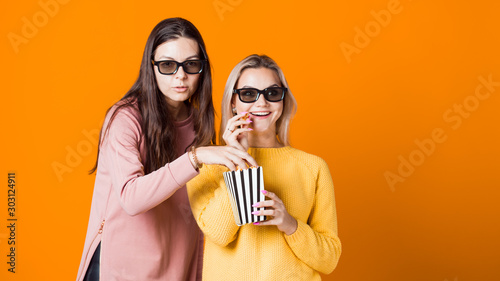 Two friends watch a movie or TV series and eat popcorn. Two young women fans of the movie 