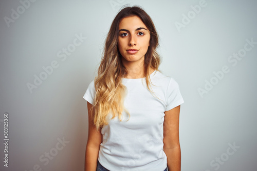 Young beautiful woman wearing casual white t-shirt over isolated background Relaxed with serious expression on face. Simple and natural looking at the camera.